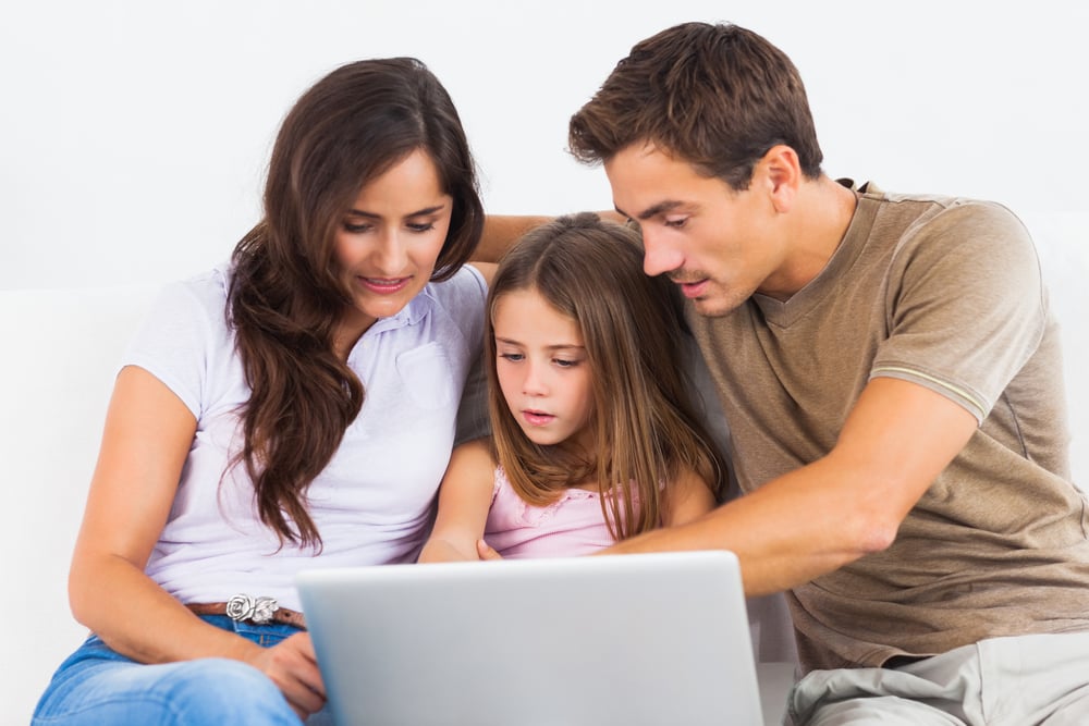 Parents with child using laptop for real-time childcare updates