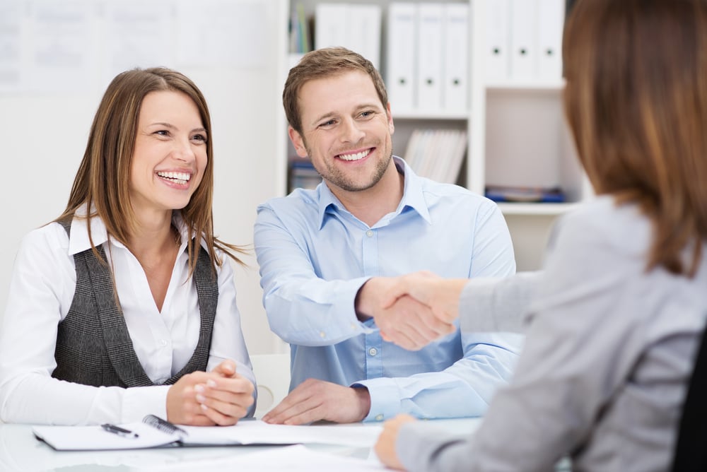 Smiling parents shaking hands with a childcare educator