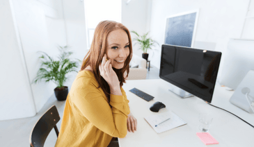 woman smiling on cell phone at desk - organizing her enrollment process