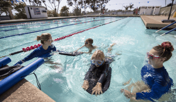 children swimming with ymca instructors in lap pool
