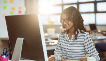 woman with glasses smiling at computer