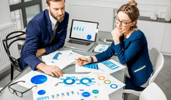 Man and woman looking at spreadsheets - trying to figure out the biggest marketing mistakes