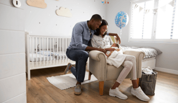 young couple holding infant baby boy in nursery room