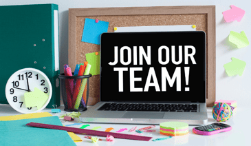desk with colorful pens and sticky notes. laptop open and says 'join our team!'