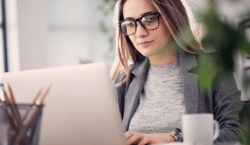 woman with glasses working on computer