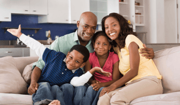 family of four with two young children sitting on couch