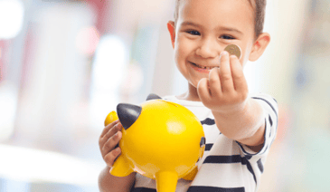 young boy holding piggy bank and coin