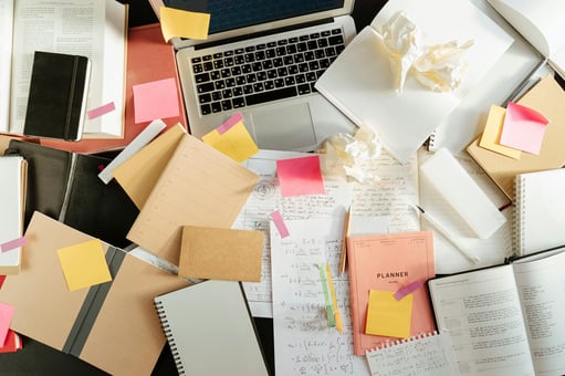 Overwhelming paperwork beside digital tools